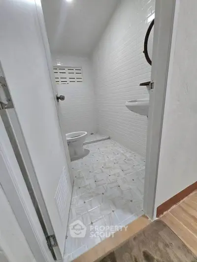 Compact bathroom with white tiles and basic fixtures, ideal for small spaces.