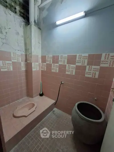 Unique rustic bathroom with pink tiles and traditional water basin, perfect for a vintage touch.
