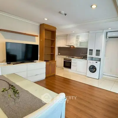 Modern open-plan living room with kitchen, featuring TV, washing machine, and oven.