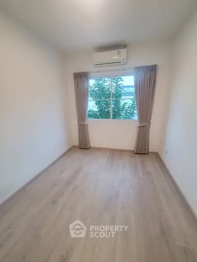 Spacious empty bedroom with large window and air conditioning, perfect for customization.