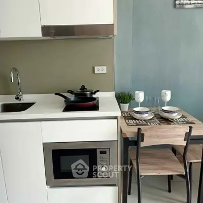 Modern compact kitchen with dining area, featuring microwave and sleek cabinetry.