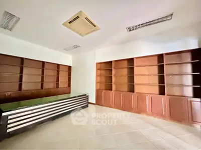 Spacious office interior with built-in wooden shelves and modern lighting
