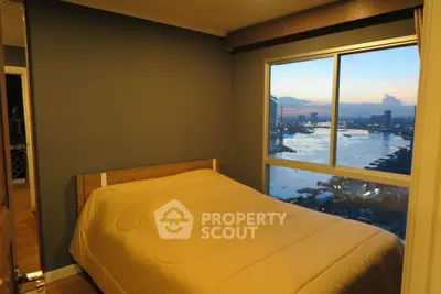 Cozy bedroom with stunning river view from large window at sunset