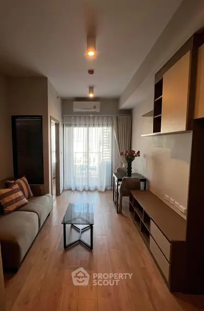 Modern living room with wooden flooring and stylish furniture, featuring a cozy sofa and elegant decor.