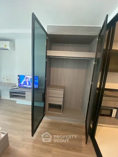 Modern apartment interior with open wardrobe and TV in living area