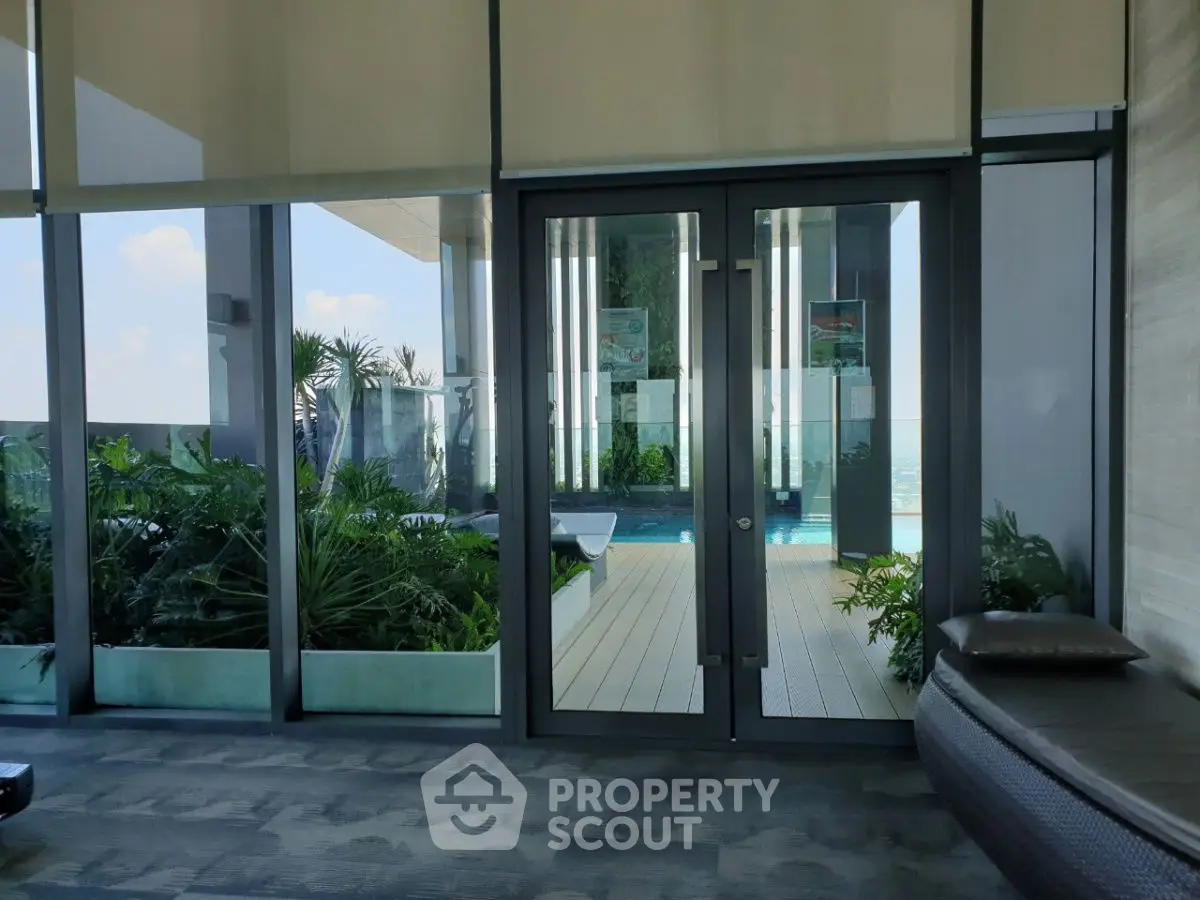 Luxurious rooftop pool with modern glass doors and lush greenery