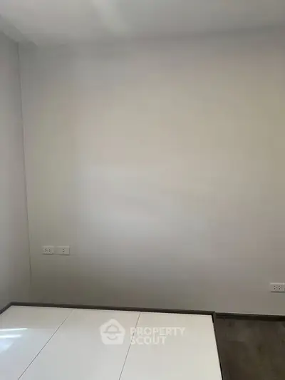 Minimalist bedroom with white walls and modern flooring, perfect for a serene living space.