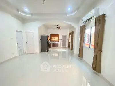 Spacious open-plan living room with modern kitchen and large windows.