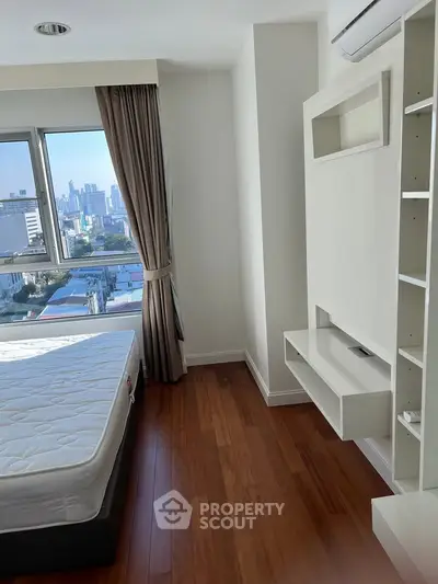 Modern bedroom with city view and hardwood floors in high-rise apartment