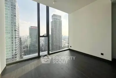 Spacious modern room with floor-to-ceiling windows offering stunning city skyline views.