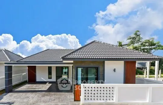Modern single-story house with tiled roof and spacious driveway under a clear blue sky.