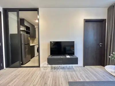 Modern living room with sleek TV setup and view into a compact kitchen
