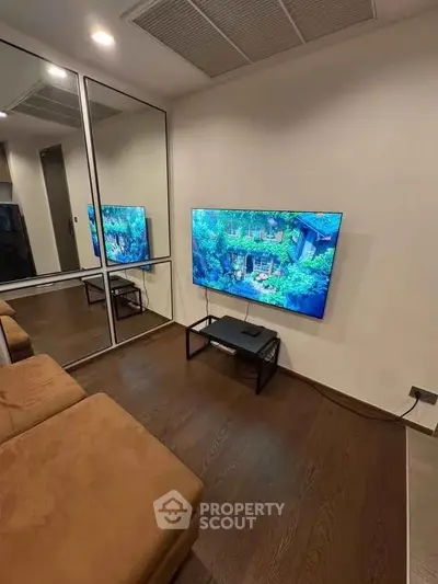 Modern living room with wall-mounted TV and mirrored closet doors.