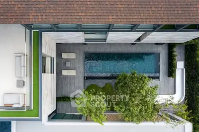 Stunning aerial view of modern luxury home with private pool and lush greenery.