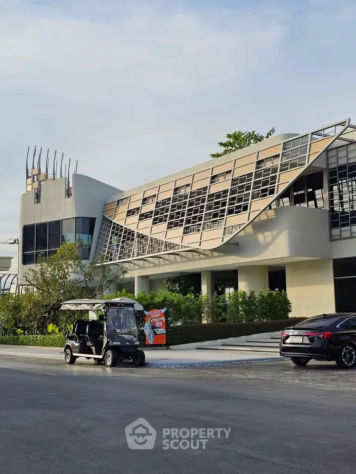 Modern architectural building with unique design and sleek facade, featuring a golf cart in the foreground.