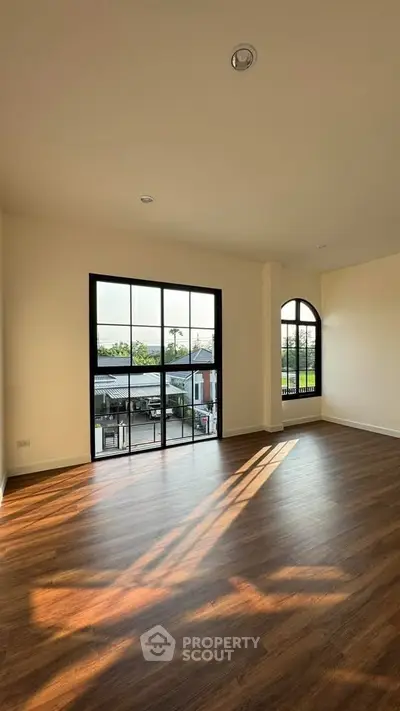 Spacious room with large windows and wooden flooring, offering abundant natural light and scenic views.