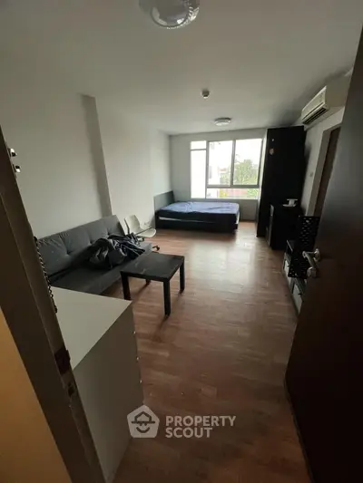Cozy studio apartment with modern furnishings and large window view.