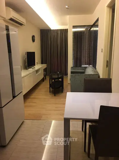 Modern living room with sleek furniture and open layout, featuring a stylish kitchen and cozy seating area.