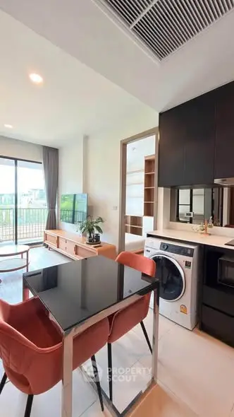 Modern open-plan living room with dining area and kitchen, featuring sleek furniture and a balcony view.