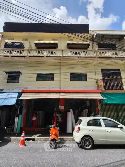 Street view of a commercial building with parked vehicles and vibrant awnings.
