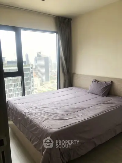 Modern bedroom with large window offering stunning city view in high-rise apartment.