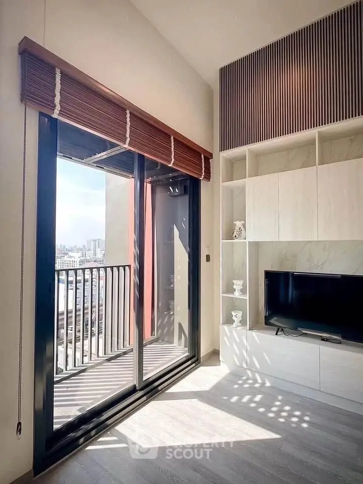 Modern living room with balcony view, featuring sleek TV unit and stylish decor.
