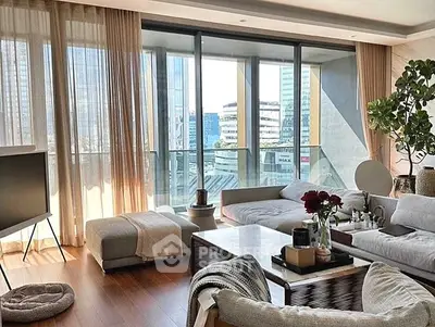 Luxurious living room with floor-to-ceiling windows and city view, modern decor and cozy seating.