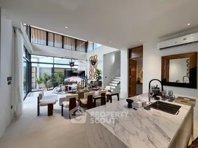 Luxurious open-plan living room with modern kitchen and elegant dining area, featuring high ceilings and stylish decor.