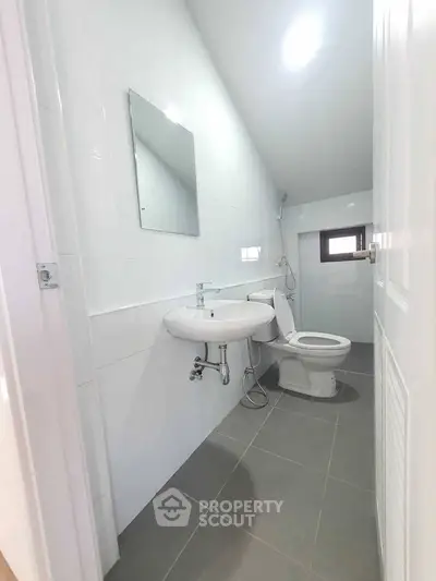 Modern minimalist bathroom with sleek white tiles and compact design.