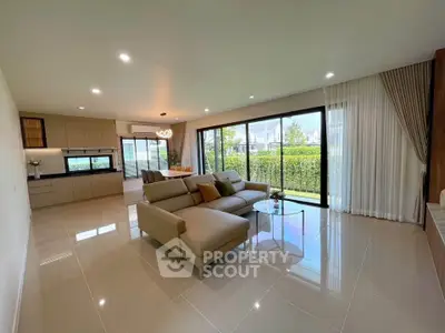 Spacious modern living room with open layout and garden view, featuring elegant furniture and natural light.