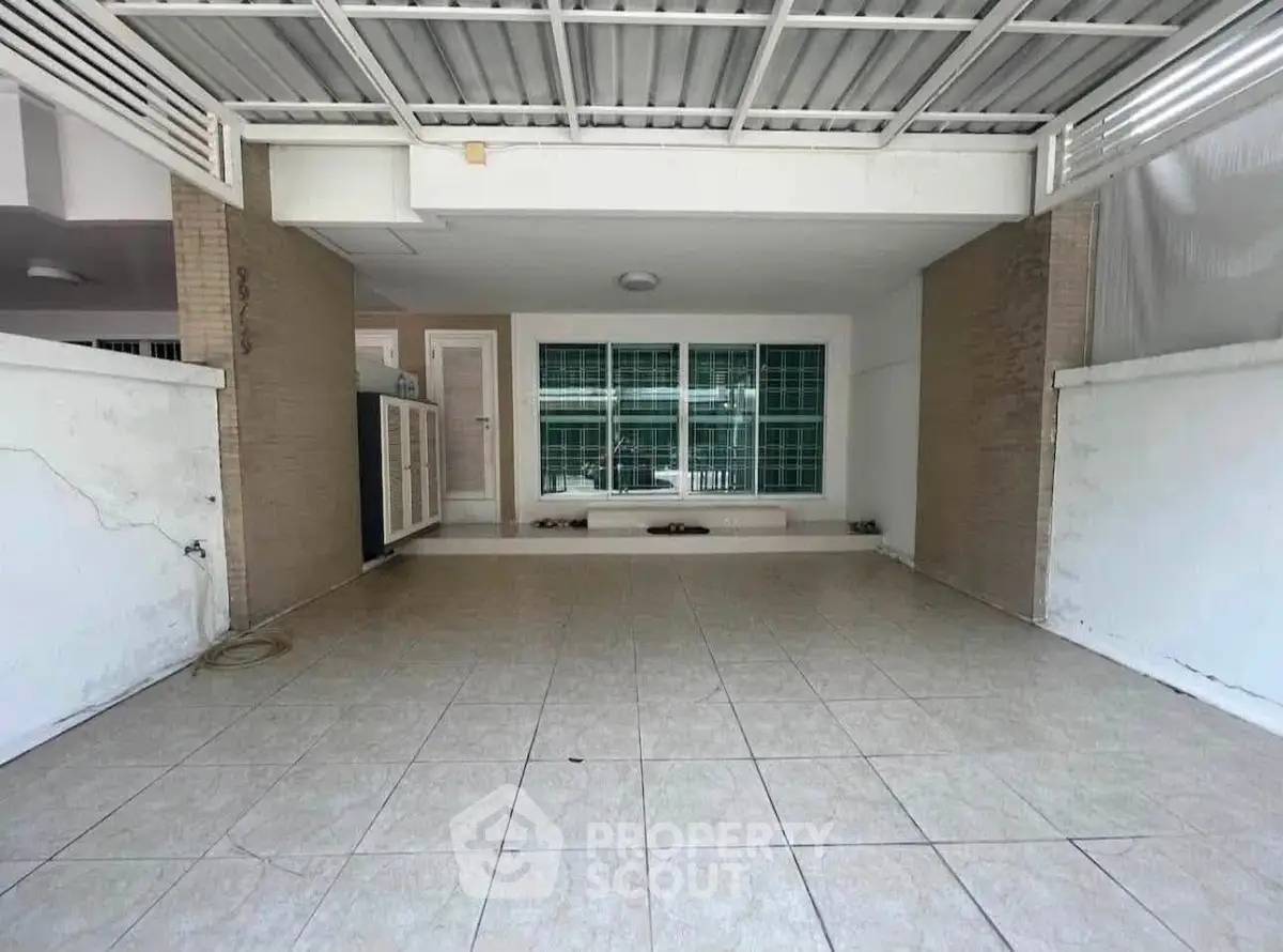 Spacious covered parking area with tiled flooring and secure gated entrance.