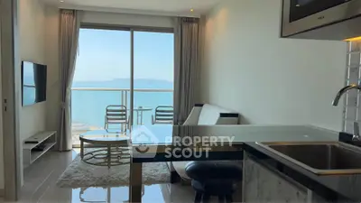 Modern living room with ocean view, sleek furniture, and open kitchen layout in a luxury apartment.