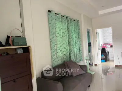 Cozy living room with modern decor and green curtains, adjacent to a kitchen area.