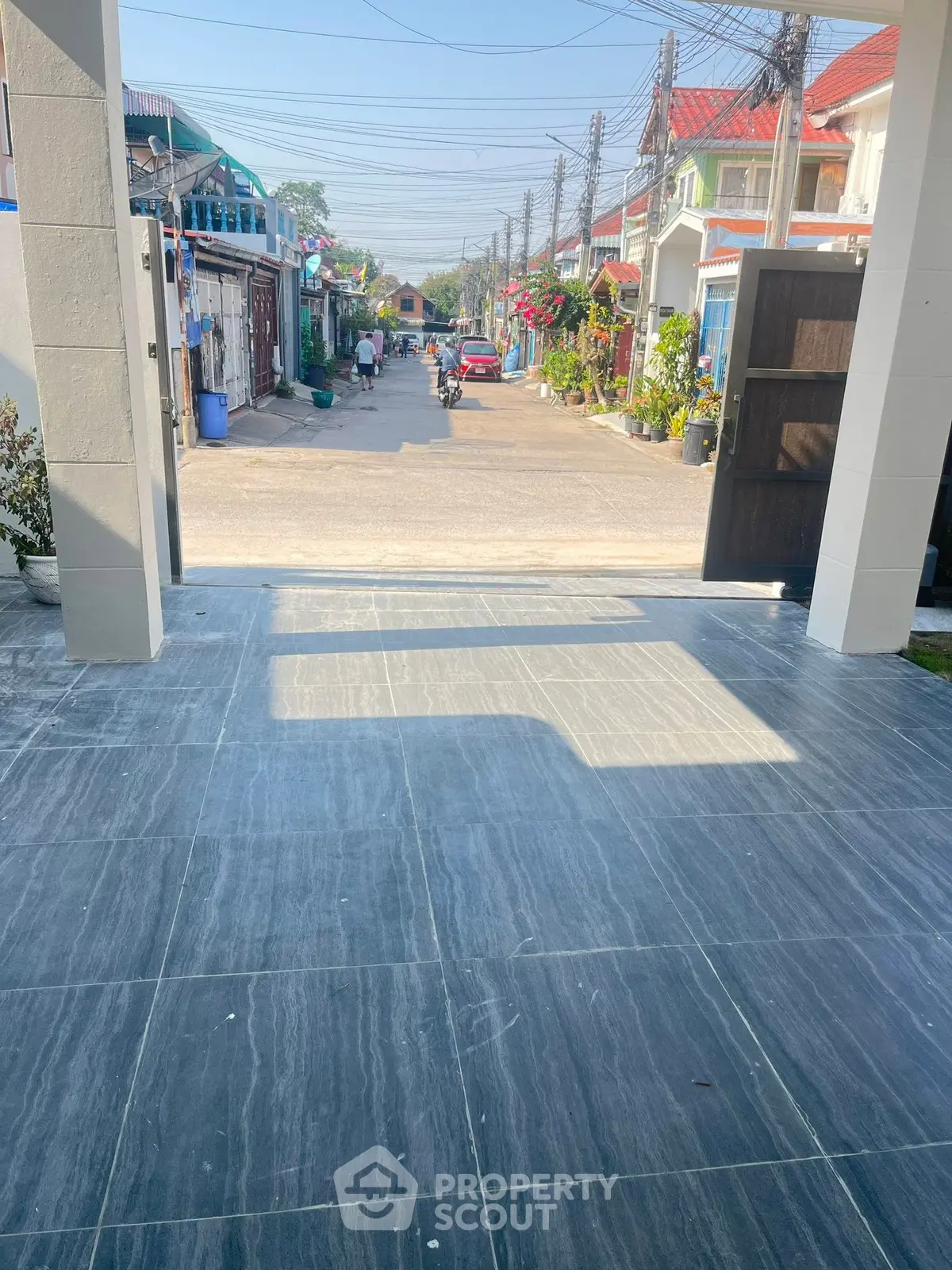 Charming residential street view from a modern tiled entrance, showcasing vibrant neighborhood life.