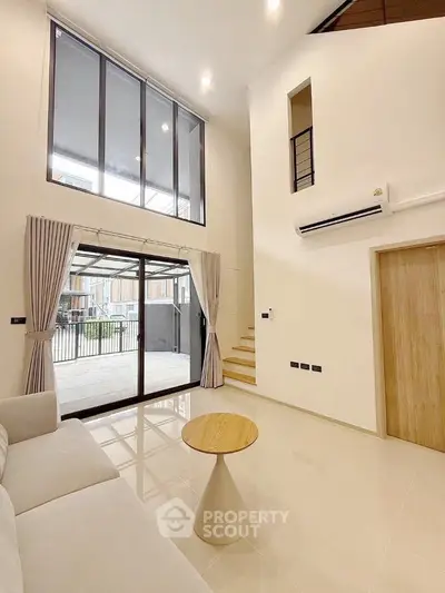 Spacious modern living room with high ceilings and large windows, featuring elegant decor and natural light.
