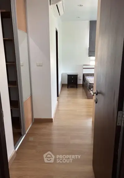 Spacious bedroom with wooden flooring and modern furnishings in a cozy apartment.