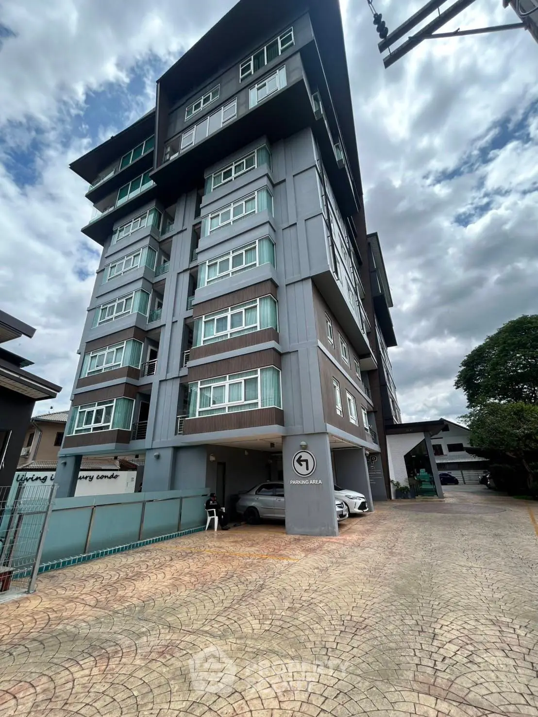 Modern multi-story residential building with spacious parking area and contemporary design.