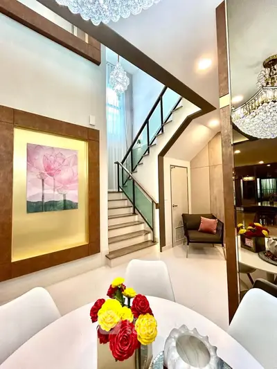 Elegant modern interior with stylish staircase and dining area, featuring chic decor and vibrant floral centerpiece.