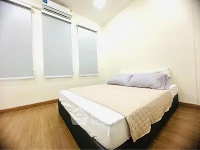 Cozy bedroom with modern decor and ample natural light from three windows.