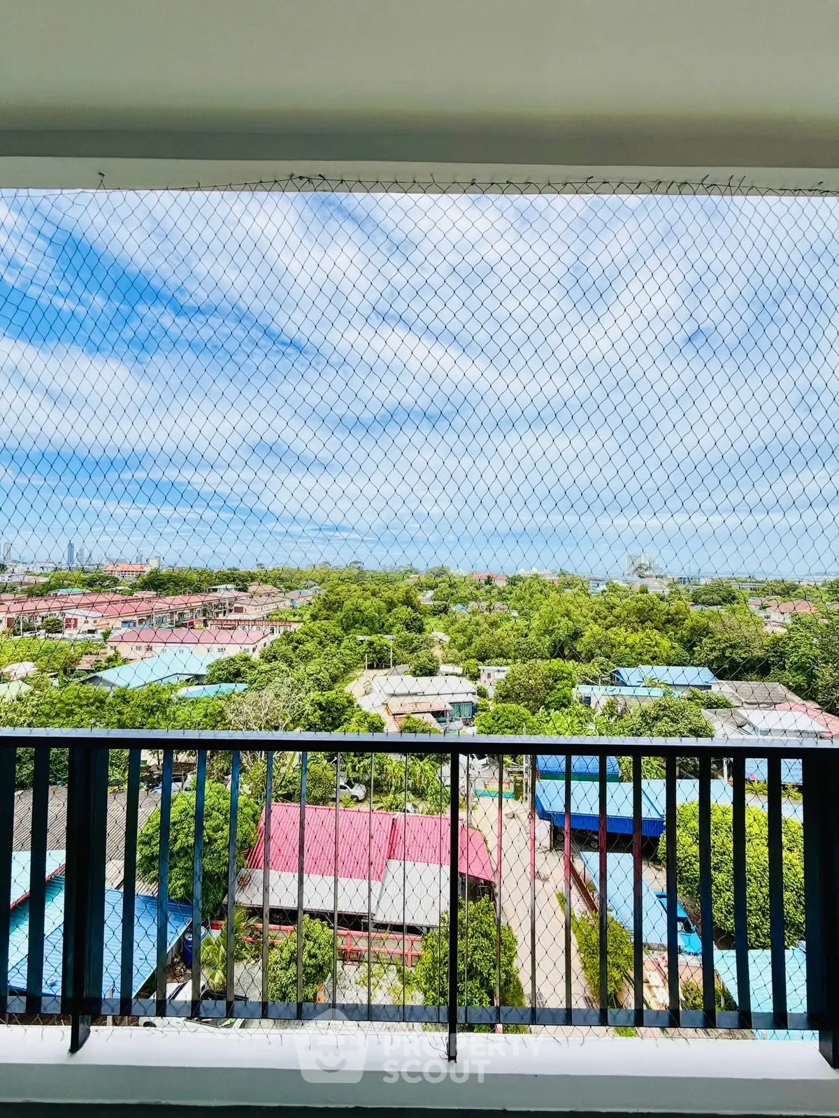 Stunning balcony view with safety net overlooking lush greenery and cityscape.
