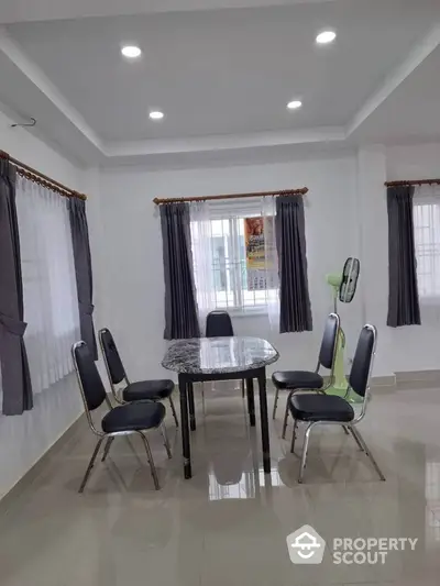 Spacious dining area with modern table and chairs, ample natural light, and elegant curtains.