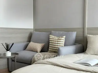Cozy bedroom with stylish gray sofa and striped cushions, perfect for relaxation and comfort.