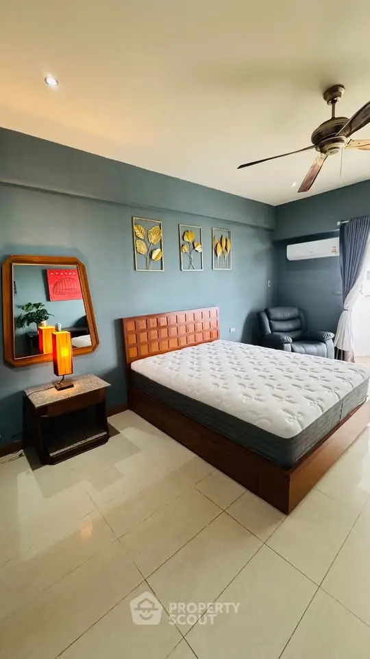 Spacious bedroom with modern decor, featuring a comfortable bed, stylish mirror, and natural light.