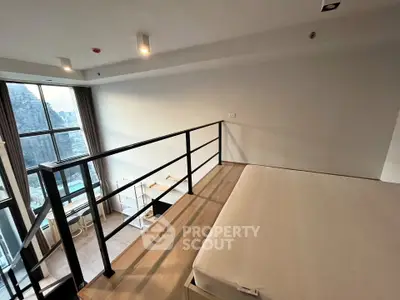 Modern loft apartment with mezzanine and large windows offering stunning city views.