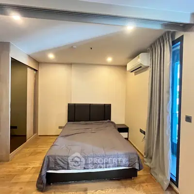 Modern bedroom with wooden flooring, large mirror, and air conditioning.