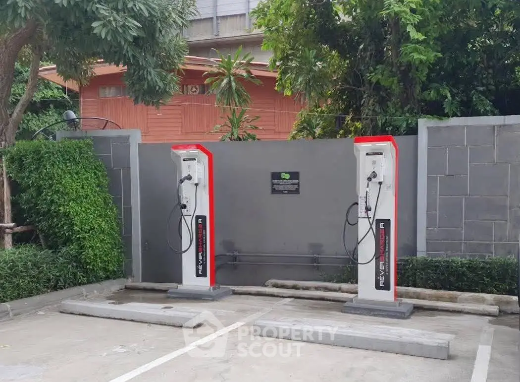 Modern electric vehicle charging stations in a residential parking area surrounded by greenery.