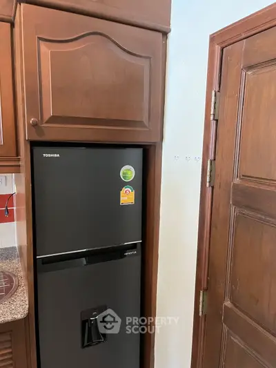 Modern kitchen with sleek black refrigerator and wooden cabinetry