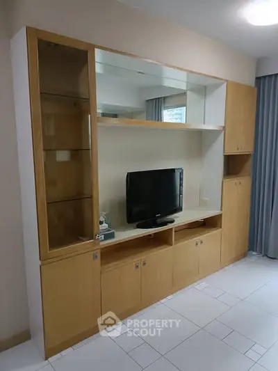 Spacious living room with modern wooden entertainment unit and sleek tile flooring.