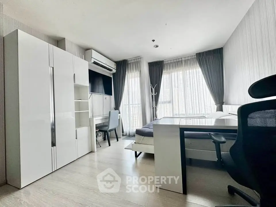 Modern bedroom with sleek furniture and large windows offering natural light