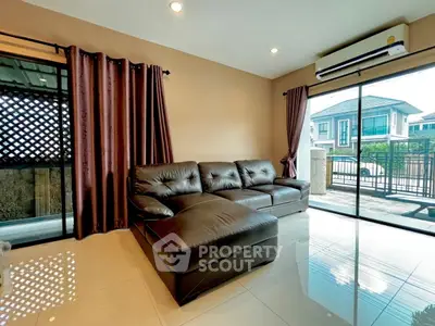 Spacious living room with modern leather sofa and large windows offering natural light.